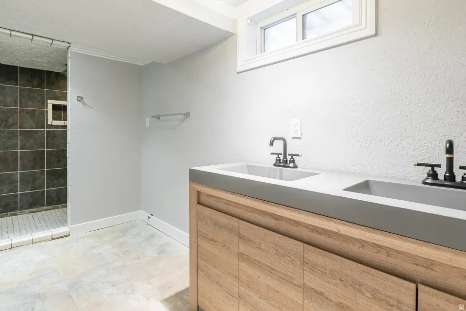 Spa-inspired primary bathroom featuring a wood-finish vanity with dual rectangular vessel sinks, integrated quartz countertop, and polished chrome wall-mounted faucets