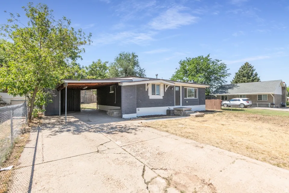 Charcoal gray exterior with white trim, featuring a covered carport and dedicated driveway