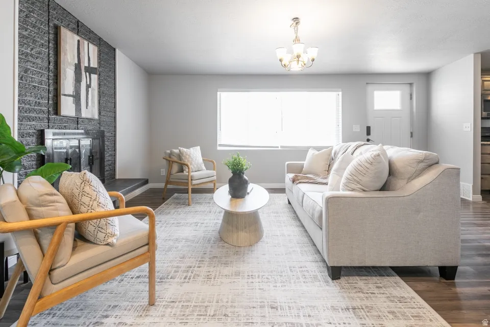 Living area featuring a black brick fireplace with dark hearth, wood-finish flooring, a large window, and a white paneled door