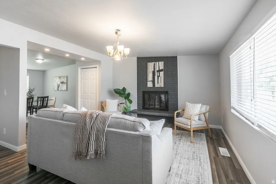 Living area featuring a floor-to-ceiling fireplace with dark stone surround, wood-finish flooring, and a chandelier light fixture