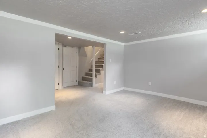 Spacious finished basement featuring pristine carpet flooring, recessed ceiling lighting, and clean drywall construction