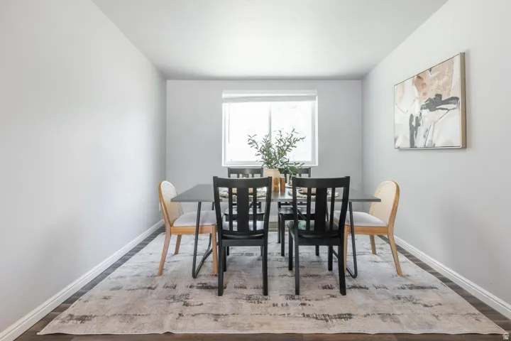 Dining area featuring wood-finish flooring, light gray wall paint, and a window with a white blind