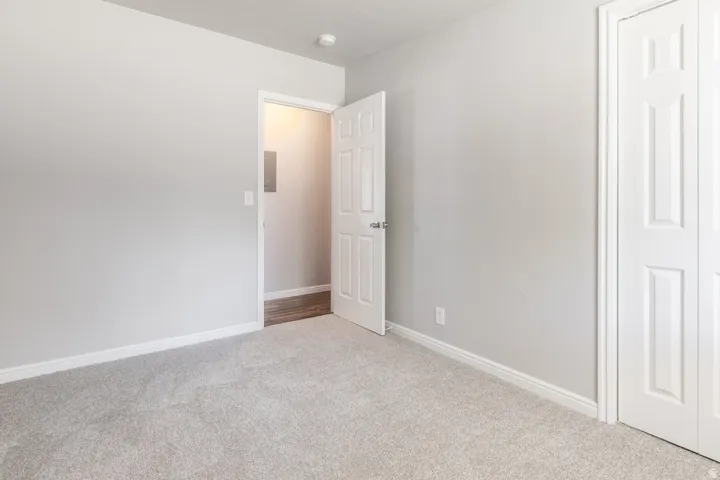 Spacious bedroom with neutral wall finishes, plush carpet flooring, and abundant natural light