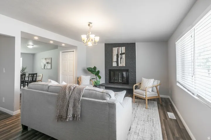 Living area featuring a floor-to-ceiling fireplace with dark stone surround, wood-finish flooring, and a chandelier light fixture