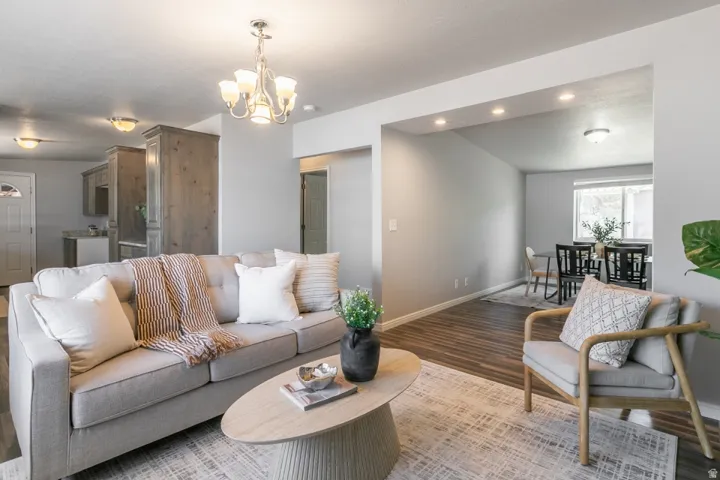 Open-concept living area featuring a gray upholstered sofa with throw pillows, wood-finish flooring throughout, and a round wood coffee table