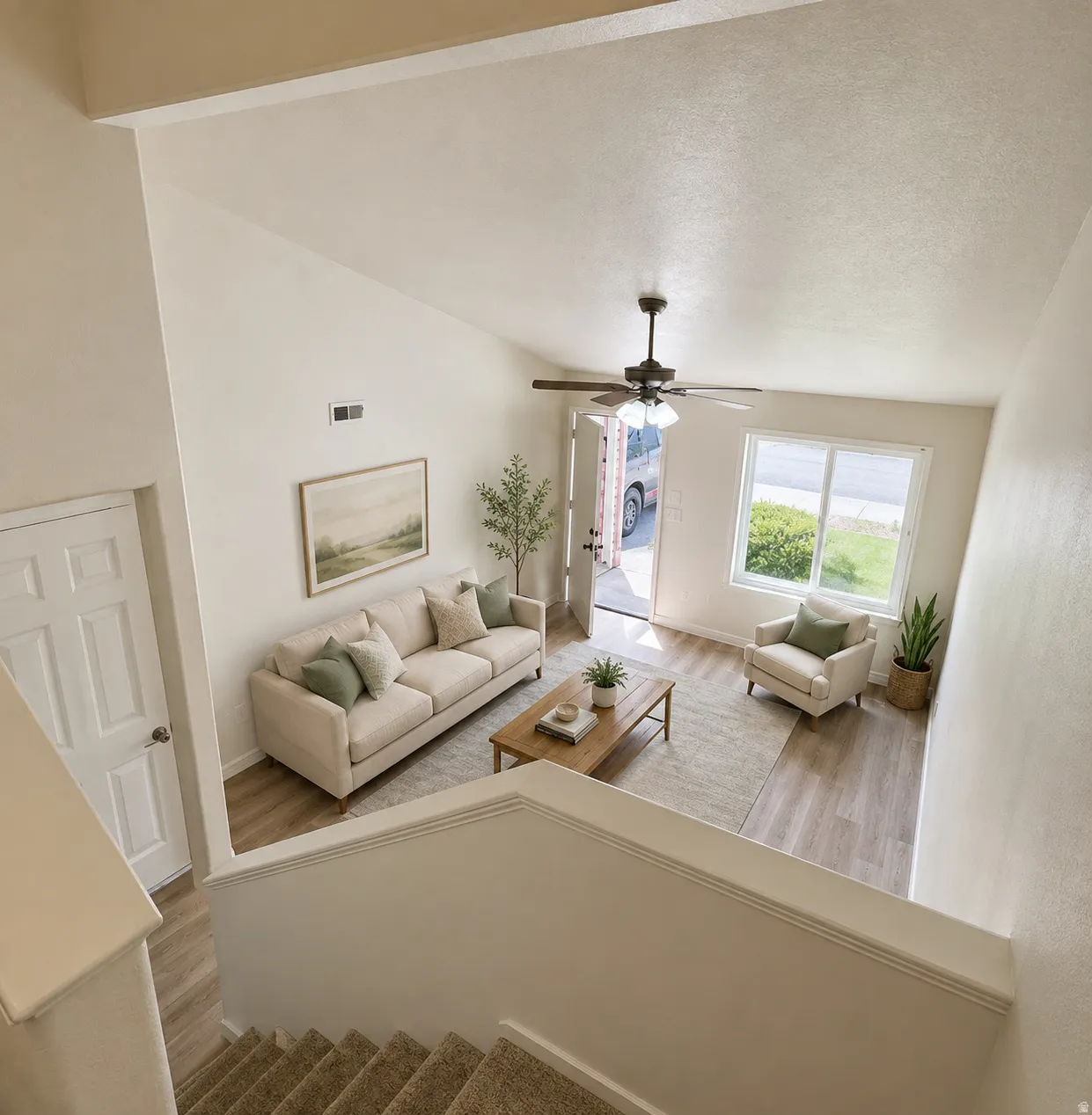 Bright, open-concept living space showcasing soaring vaulted ceilings, abundant natural light from dual glass doors and windows, and a ceiling fan with dark metal finish
