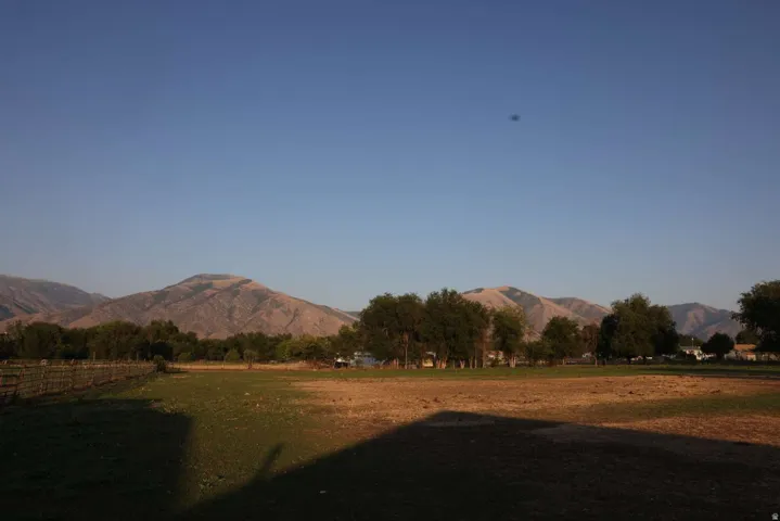 Expansive grounds featuring mature landscaping and tree-lined perimeter with mountain backdrop