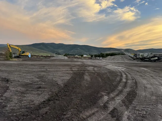 Expansive land parcel featuring a vast, level dirt surface with tire tracks present