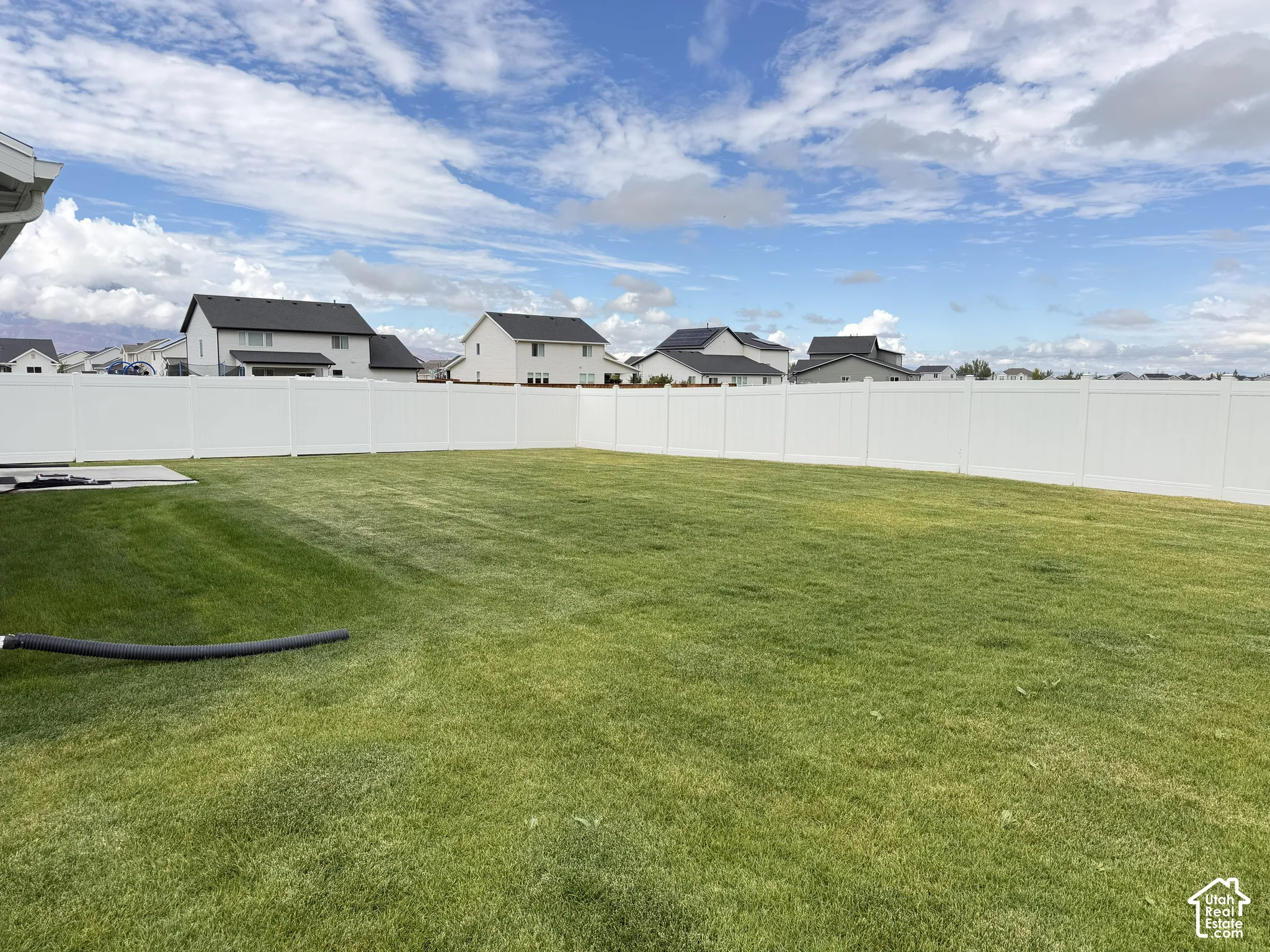 Expansive green lawn with a white privacy fence