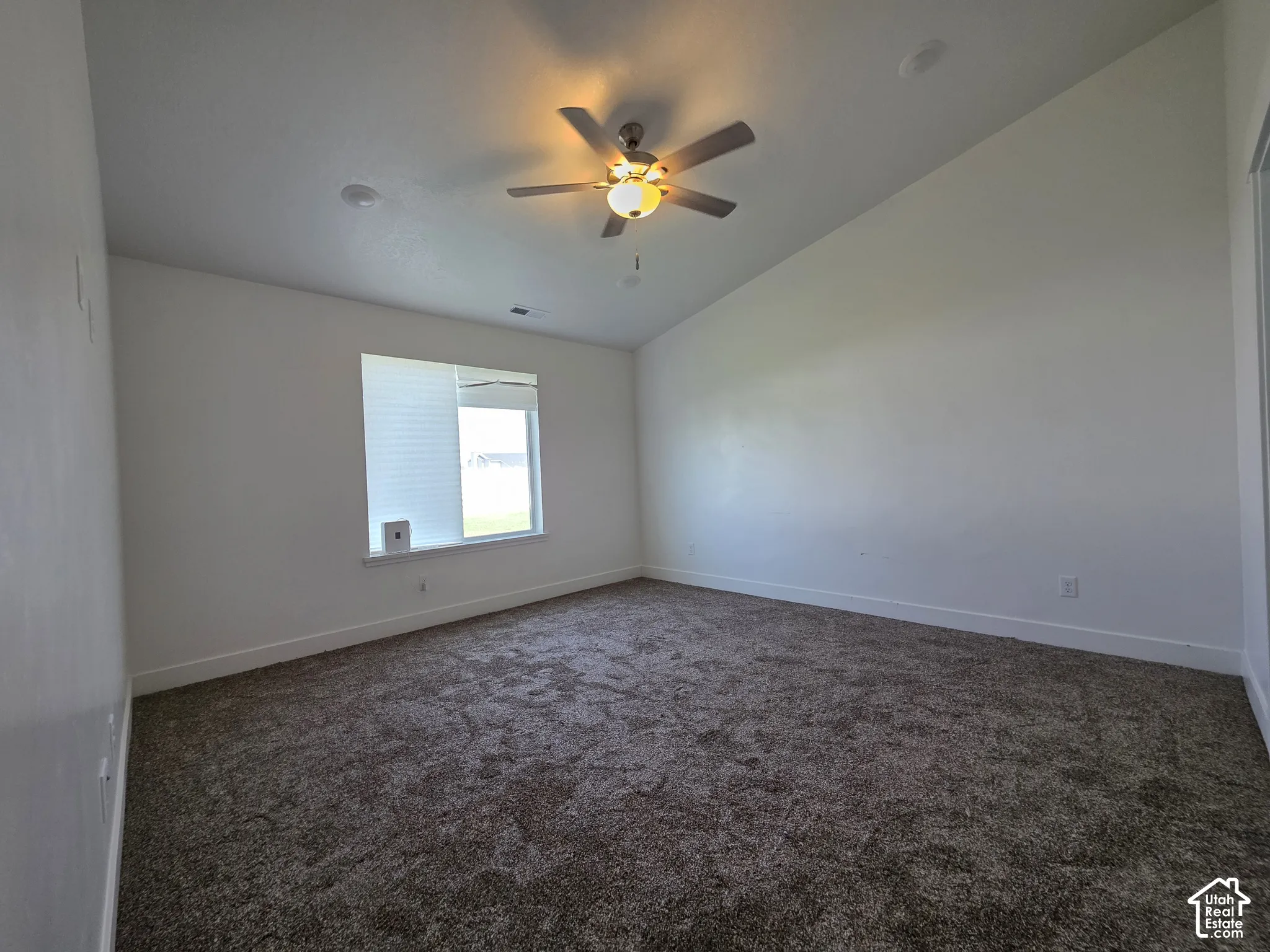 Spacious bedroom with neutral wall finishes, carpeted flooring, and abundant natural light from a large window