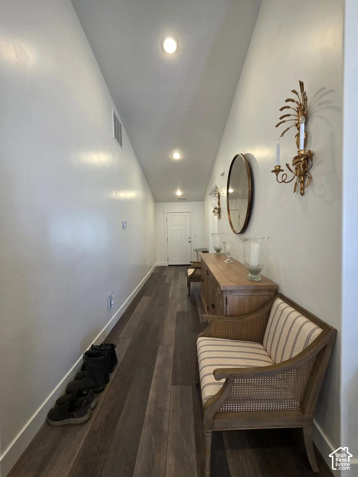Elongated entryway featuring wood-finish flooring, recessed lighting, and a paneled white door