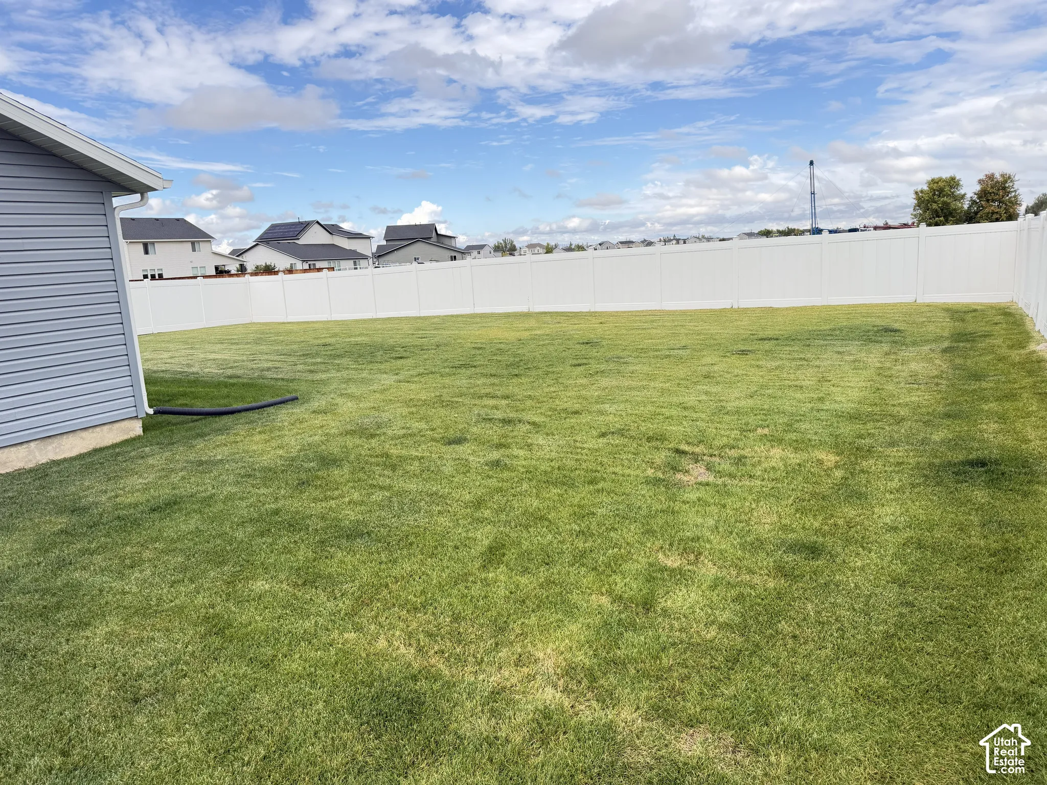 Expansive green lawn, white privacy fencing, and blue horizontal siding