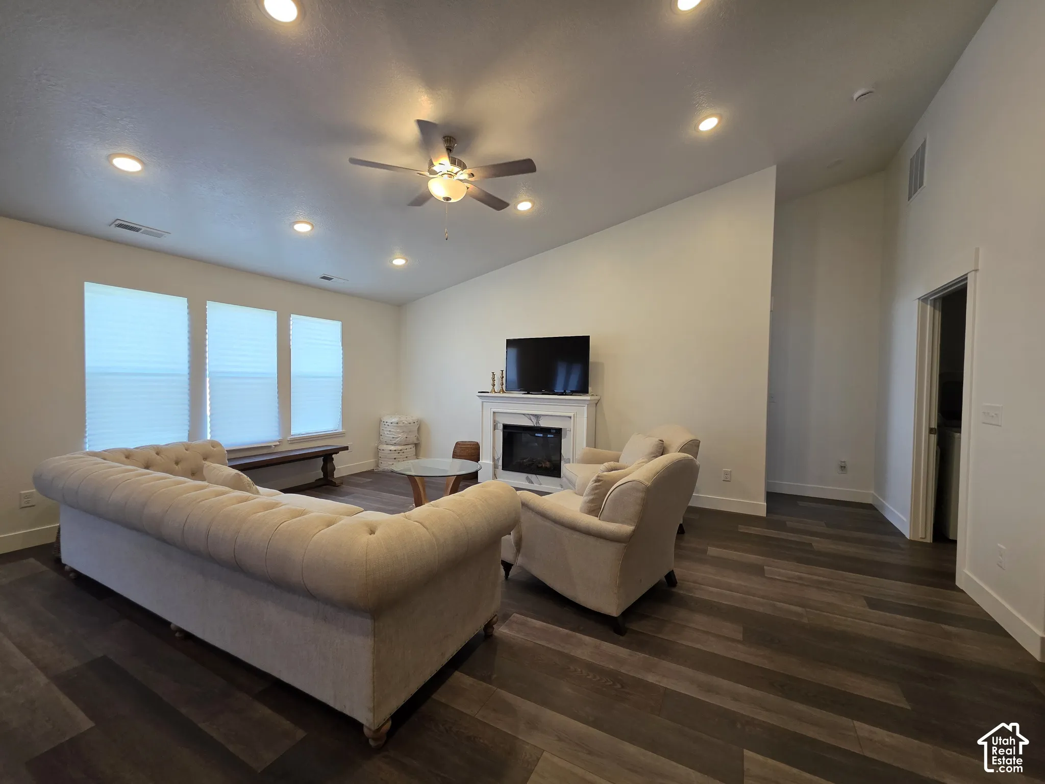 Spacious living area featuring a curved sectional sofa arrangement, wood-finish flooring throughout, and a fireplace with built-in entertainment center