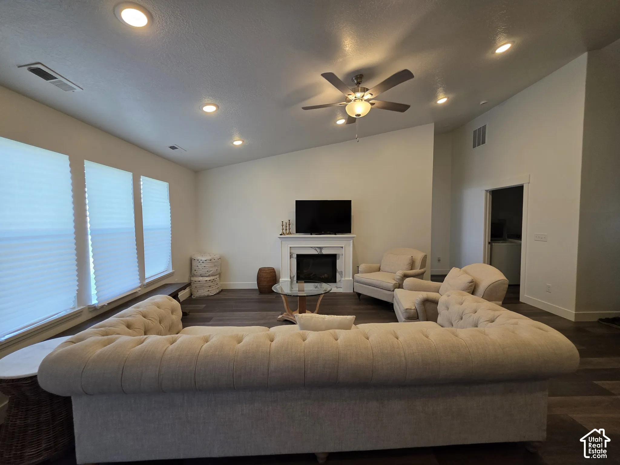 Spacious great room featuring a curved sectional sofa arrangement, wood-finish flooring, and abundant natural light from expansive waterfront windows