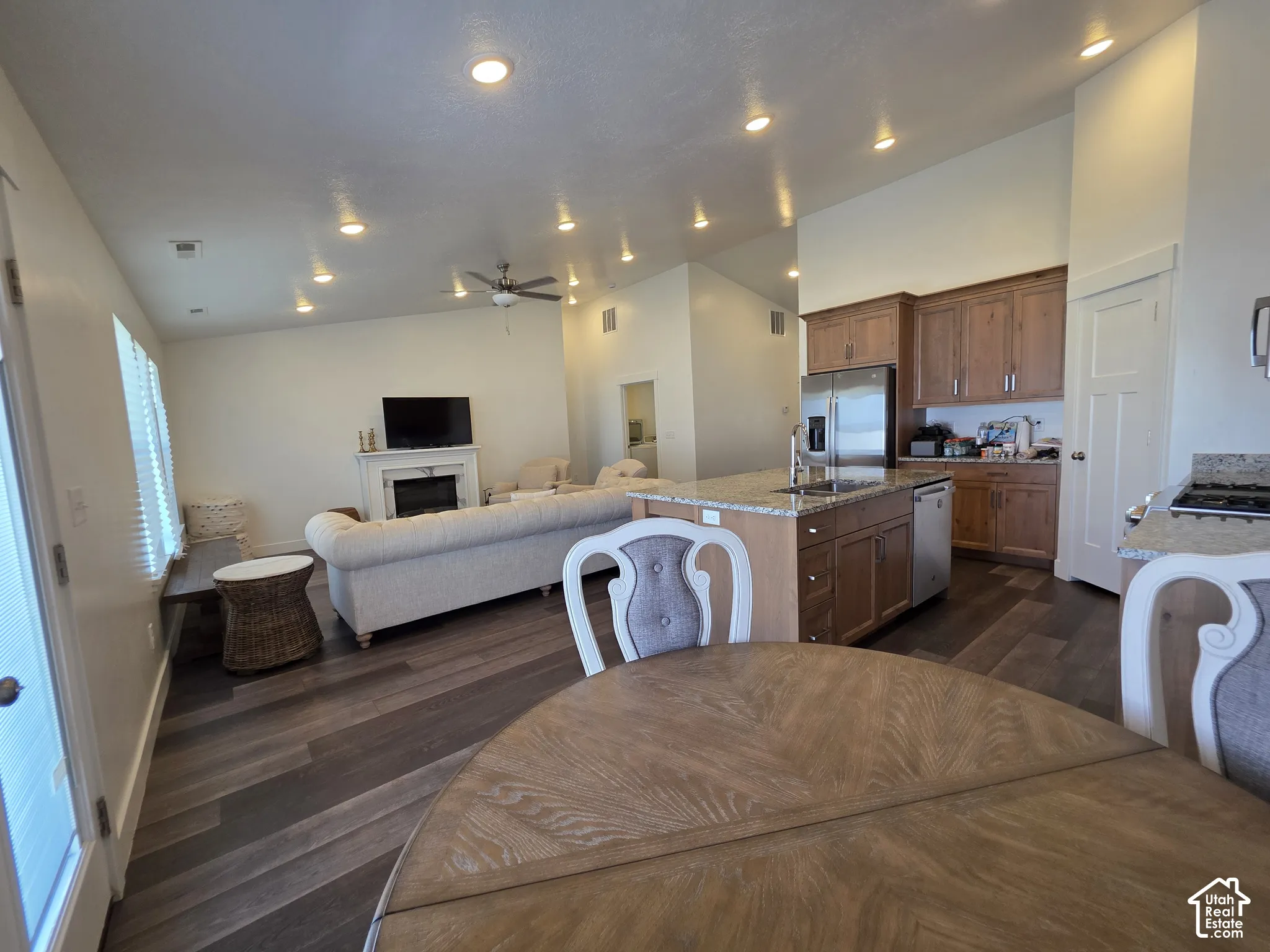 Open-concept living space featuring wood-finish flooring, recessed lighting, and a white fireplace with mantle