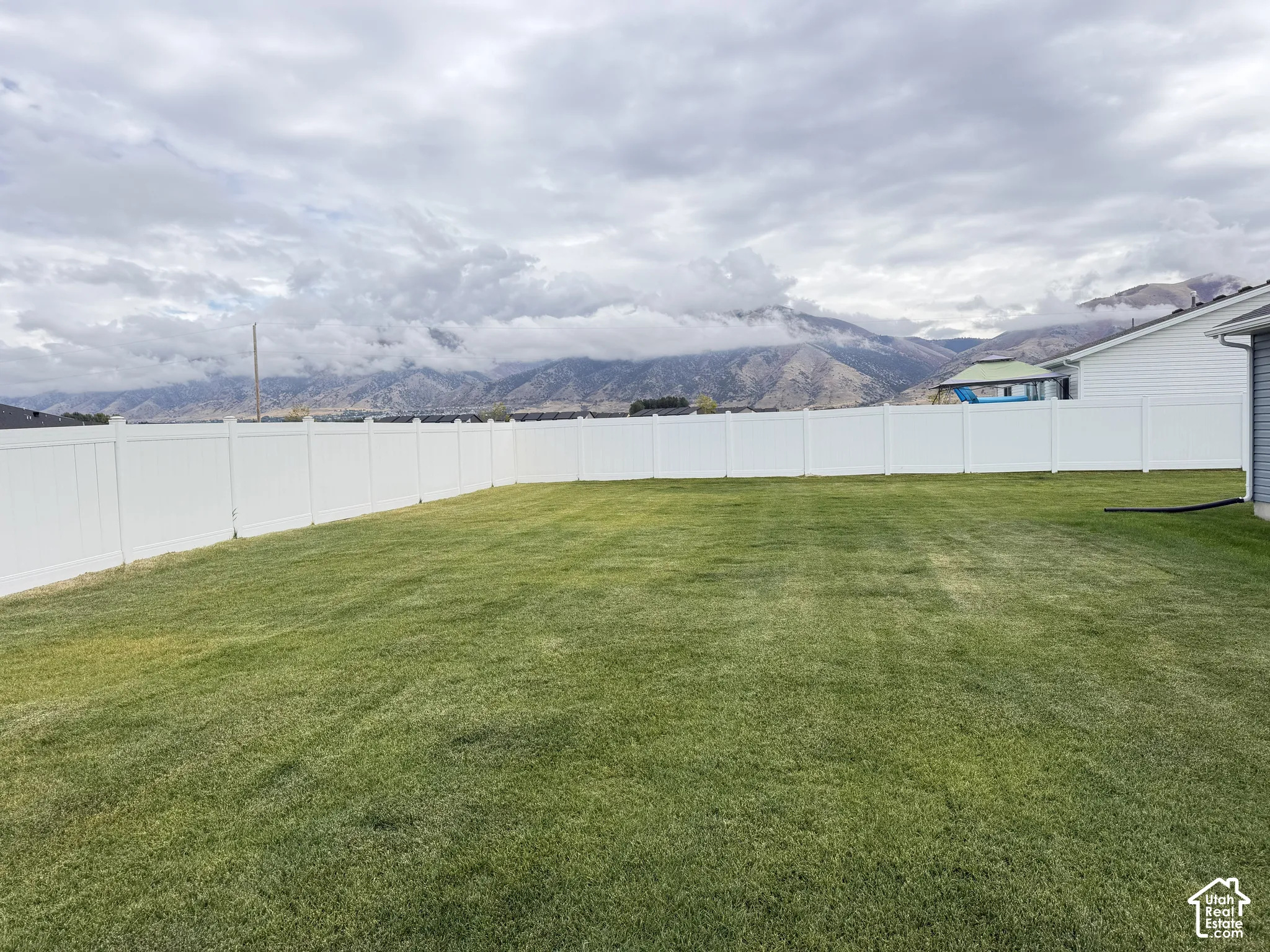 Expansive grassy lawn with a white privacy fence