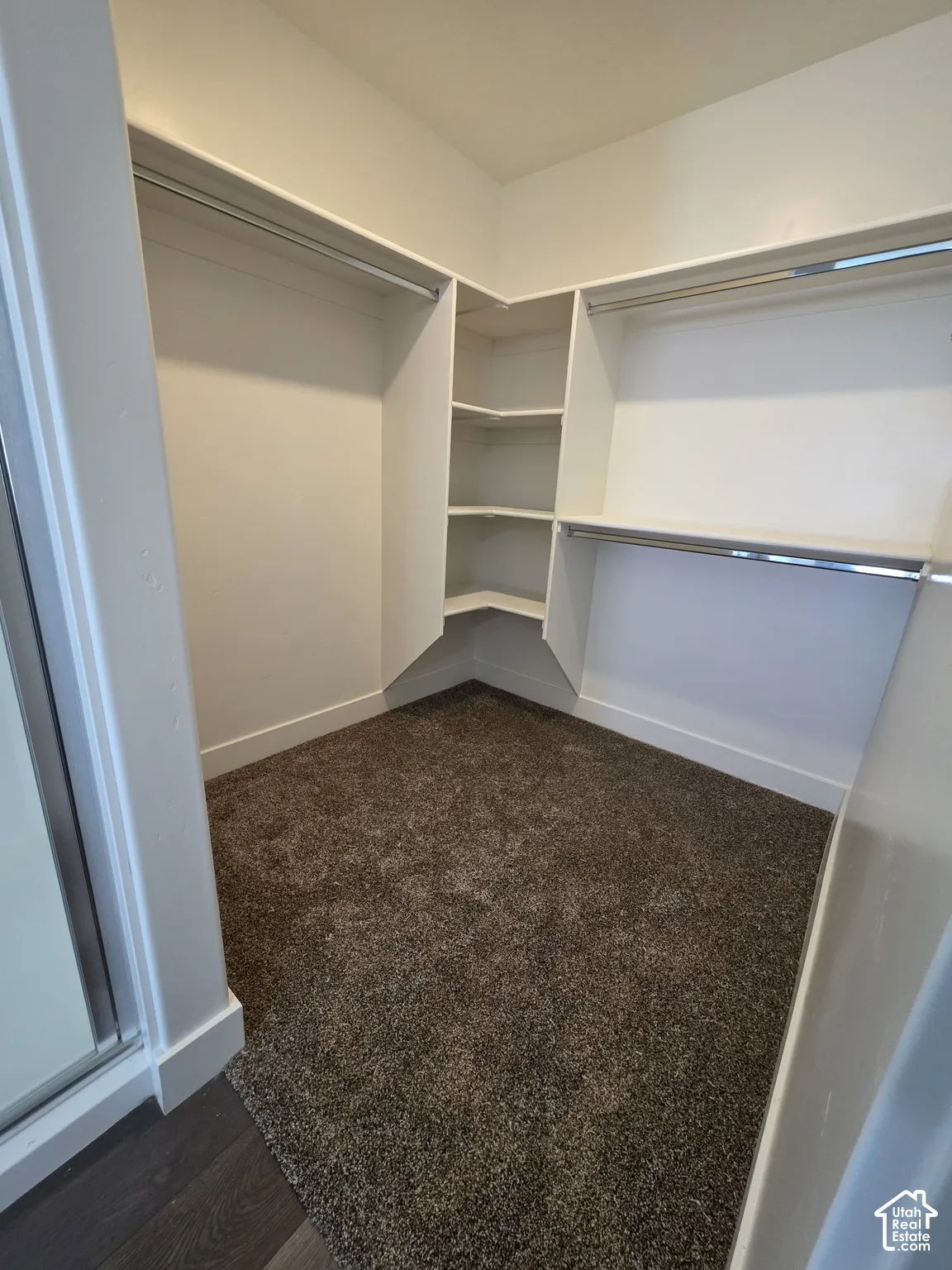 Spacious walk-in closet featuring dual clothing rods, built-in shelving with multiple compartments, carpeted flooring, and abundant storage capacity for organized wardrobe management