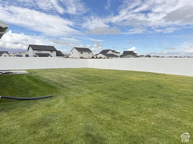 Expansive green lawn with a white privacy fence
