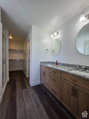 Bathroom featuring a dual vanity with a granite-style countertop, wood-finish cabinetry, and round mirrors