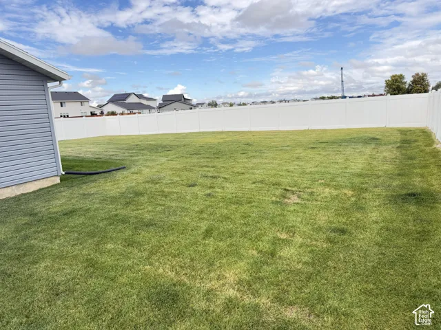 Expansive green lawn, white privacy fencing, and blue horizontal siding