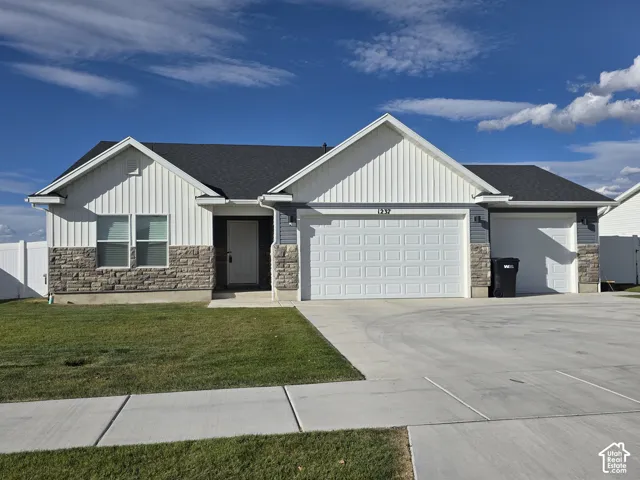 White vertical siding and grey horizontal siding exterior with stone veneer accents, a dark shingled roof, an attached two-car garage, and concrete driveway