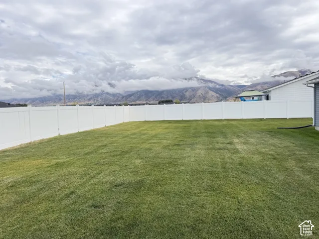 Expansive grassy lawn with a white privacy fence
