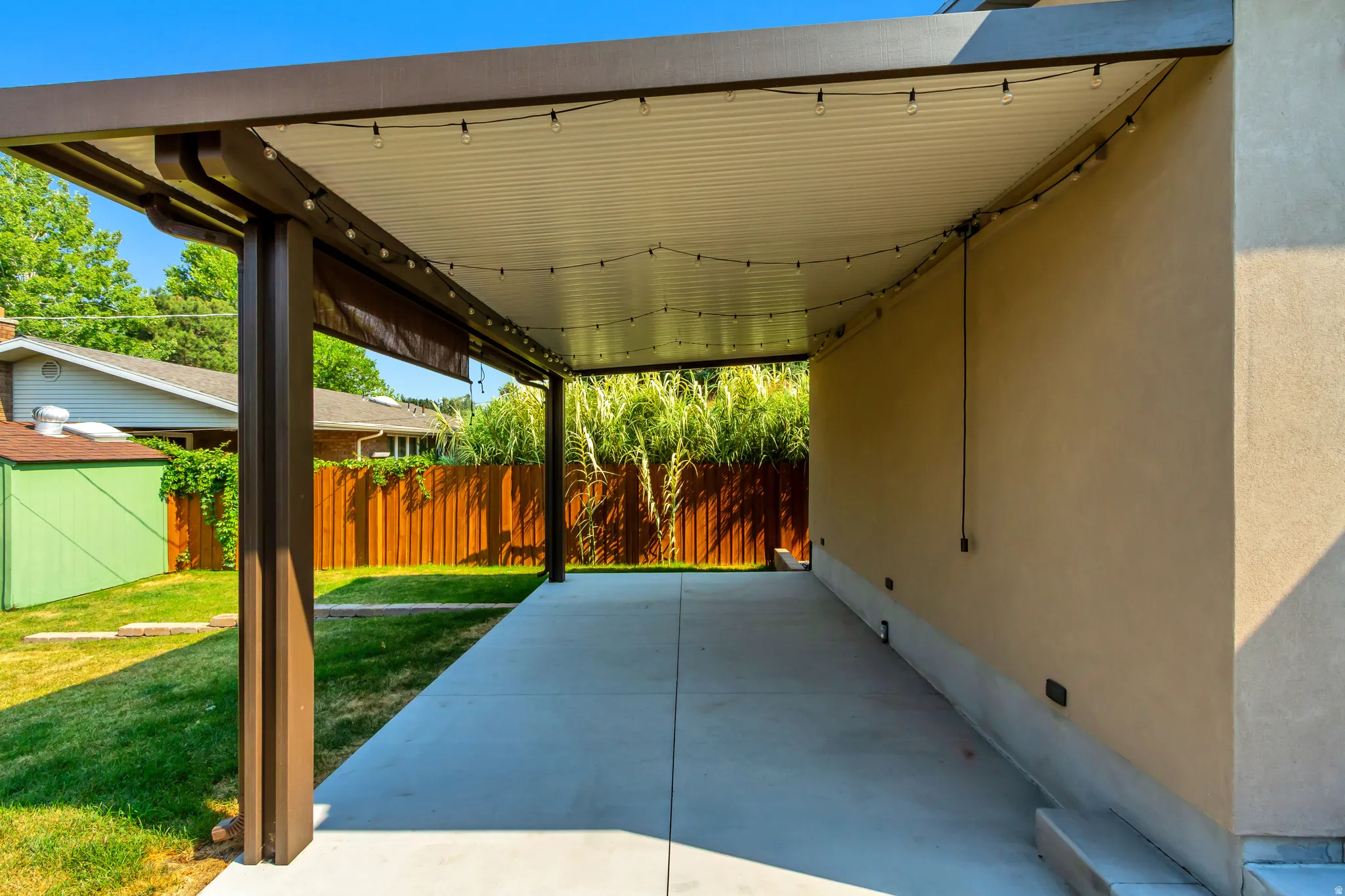 Covered patio with retractable sunshades for hosting evening barbecues and relaxation.