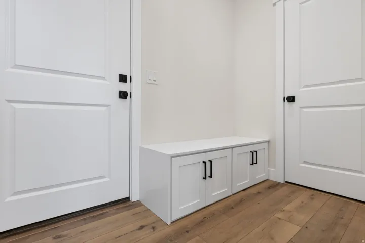 Built-in storage bench with two white cabinet doors and matte black hardware