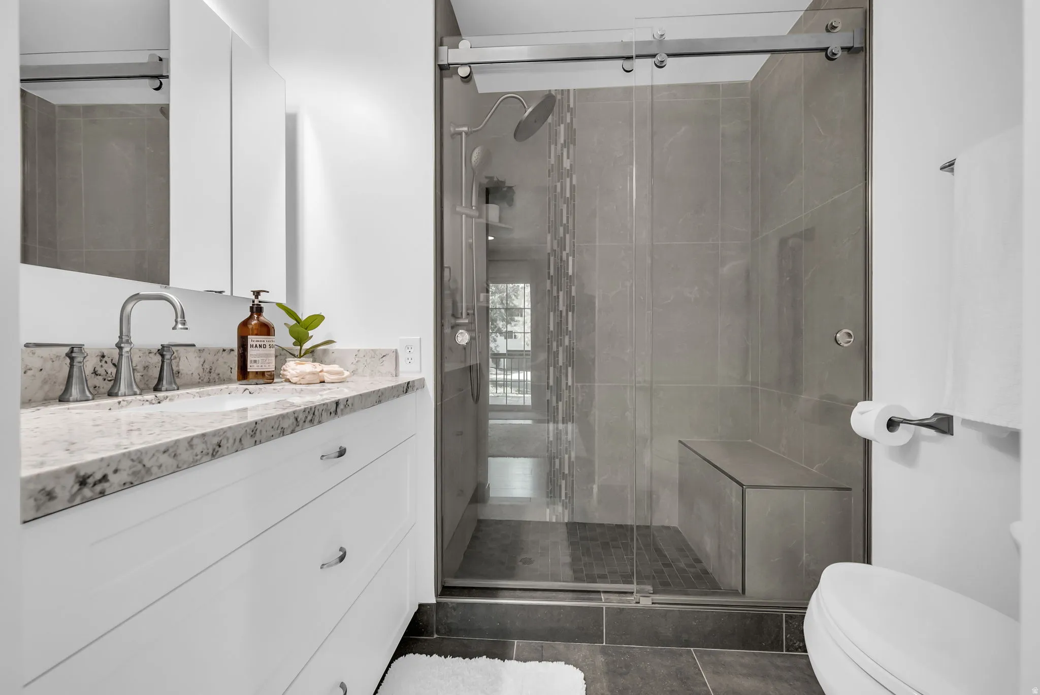 Modern bathroom featuring a floating vanity with marble-look countertop, integrated sink, and chrome faucet