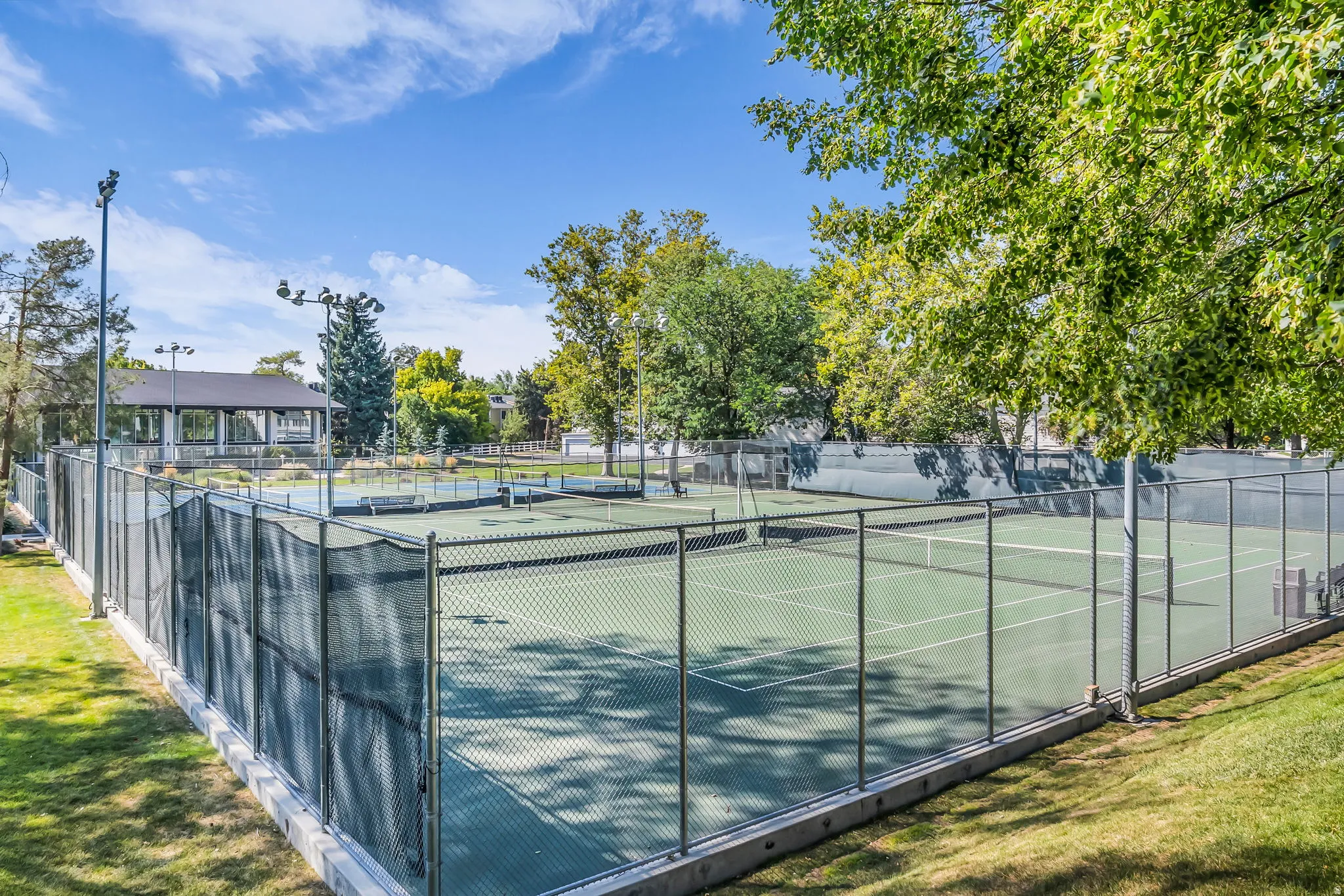 Professional-grade tennis courts featuring hard court surfaces, metal mesh fencing, and integrated lighting infrastructure