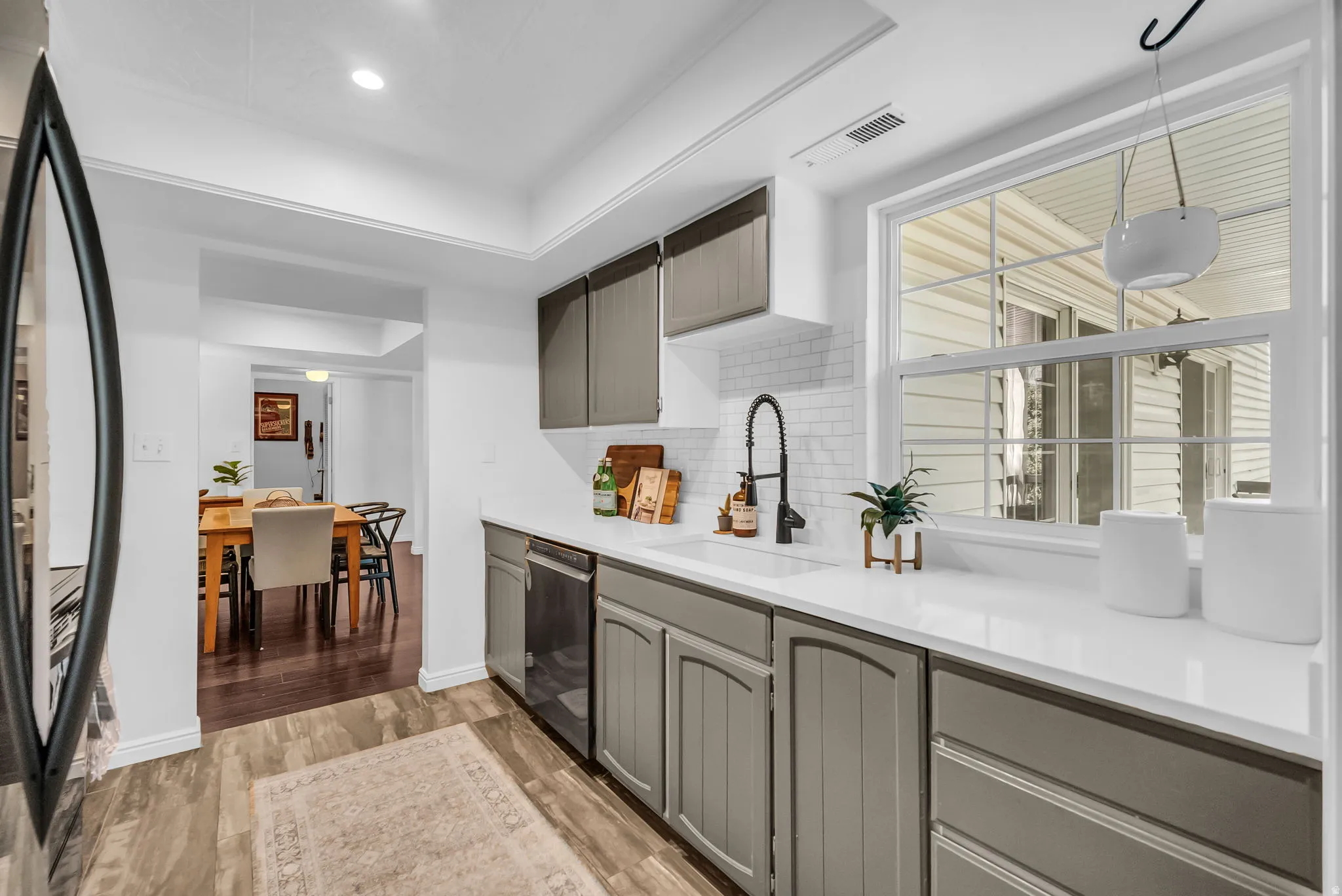 Modern galley kitchen featuring custom cabinetry with soft-close drawers, white quartz countertops, stainless steel appliances, an undermount sink with contemporary faucet, and abundant natural light from large casement windows