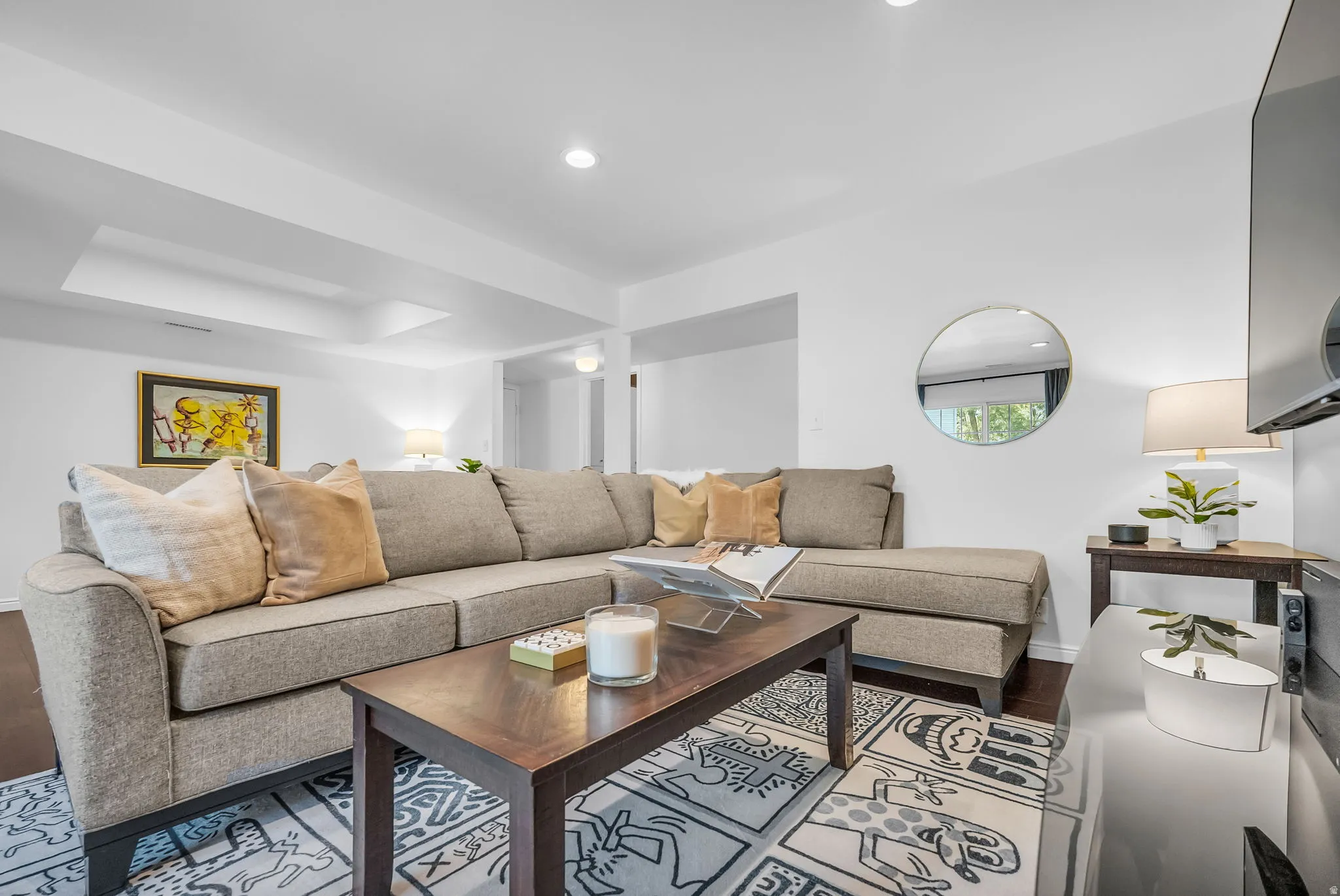 Recessed lighting illuminates this living space featuring white walls and dark wood-finish flooring