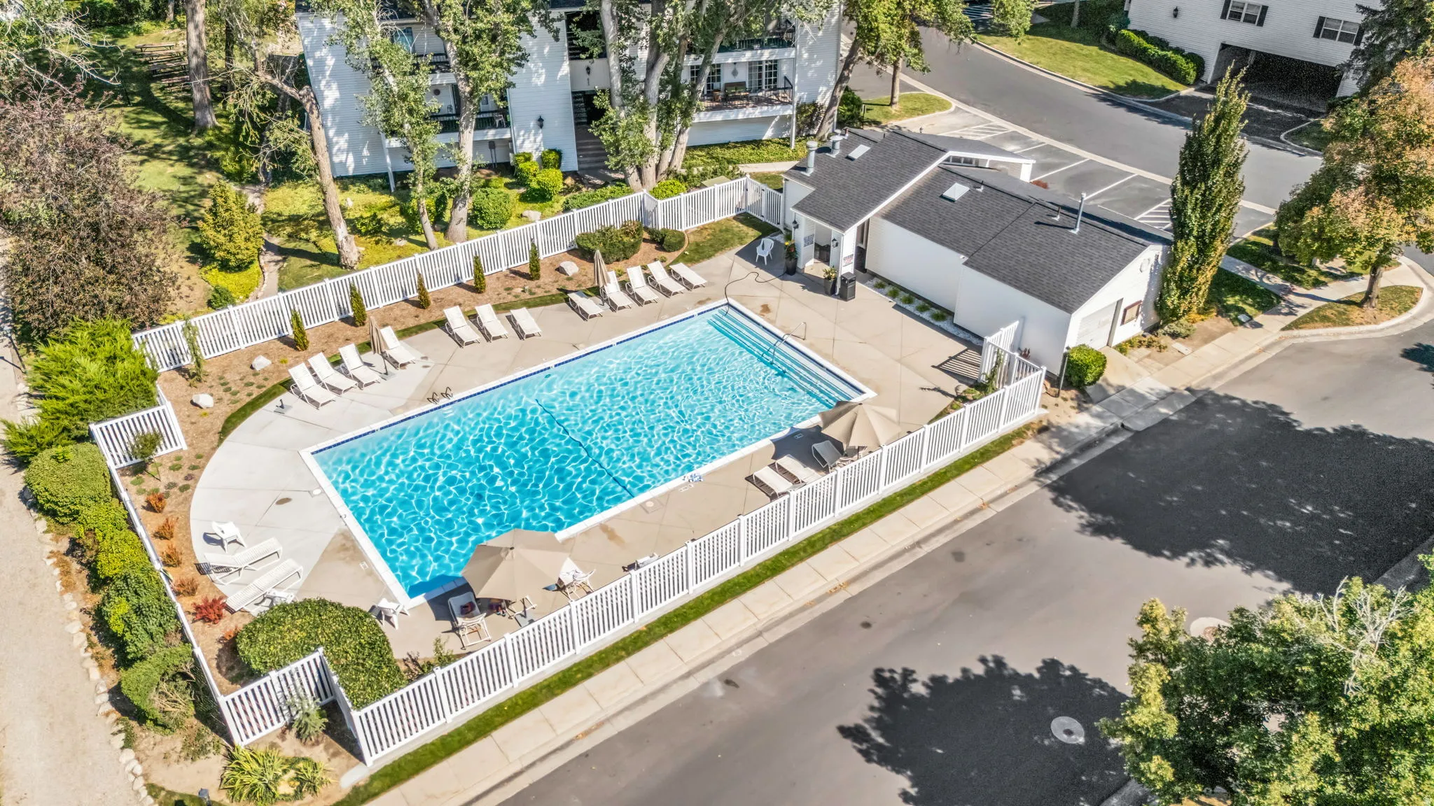 Resort-style swimming pool with crystal-clear water and generous sun deck featuring multiple loungers and umbrellas