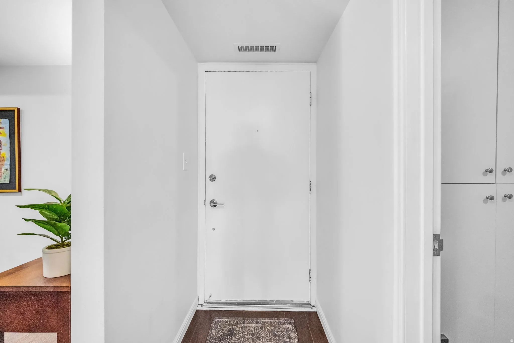 Entryway featuring a white door with brushed nickel hardware, wood-finish flooring, and crisp white walls
