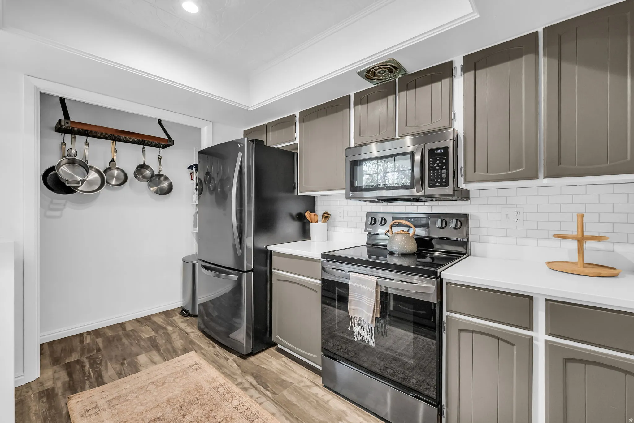 Modern kitchen featuring stainless steel appliances including a French-door refrigerator, electric range, and microwave