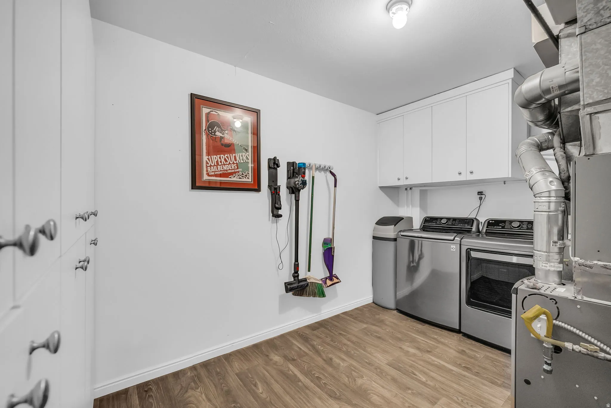 Modern kitchen featuring stainless steel appliances, white cabinetry, wood-finish flooring, and ample counter space