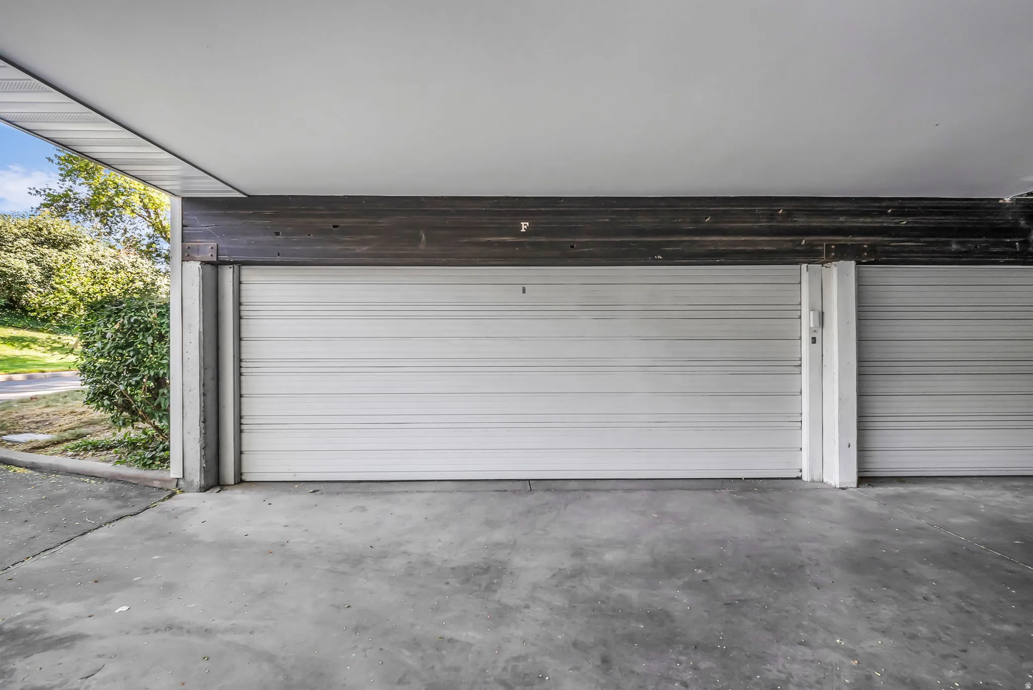 Spacious two-car garage featuring white sectional doors, polished concrete flooring, and integrated overhead storage