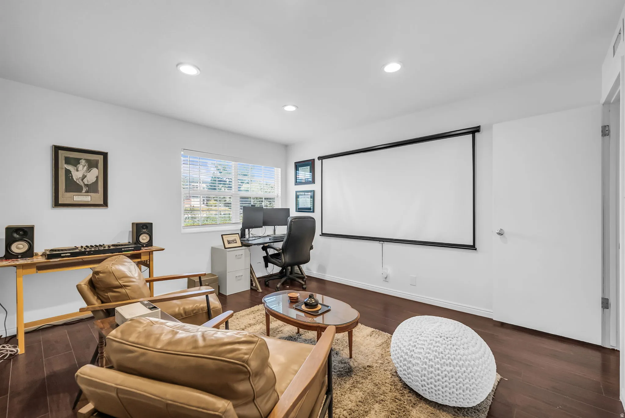 Dedicated media room featuring a large projection screen, recessed lighting, wood-finish flooring, and comfortable seating arrangement