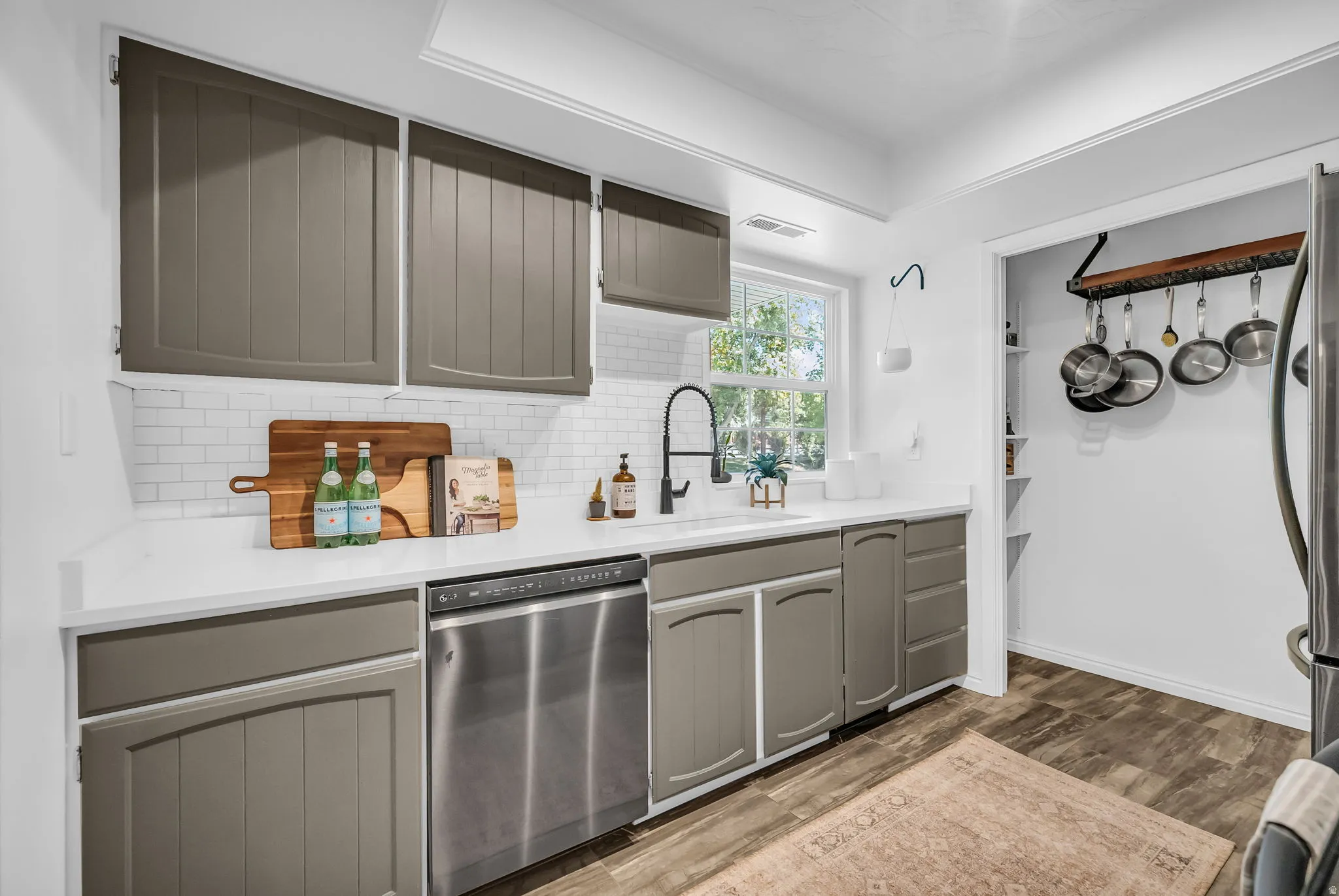 Modern kitchen featuring taupe cabinetry with brushed nickel hardware, stainless steel appliances including a dishwasher, and a gooseneck faucet