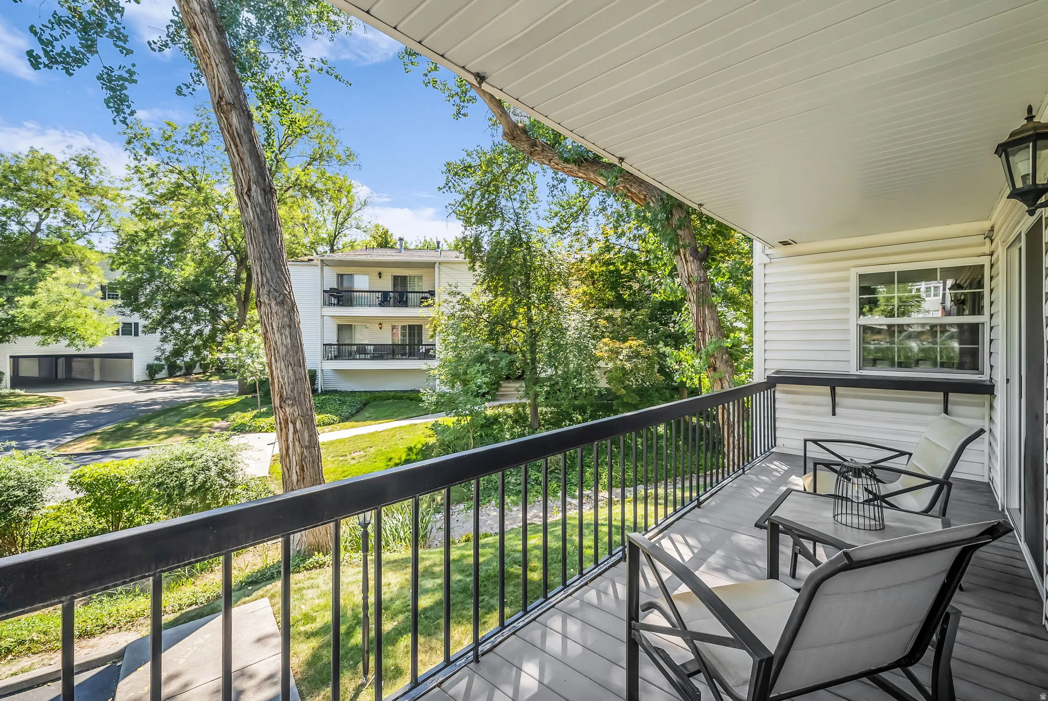 Covered balcony featuring composite decking and a black metal railing