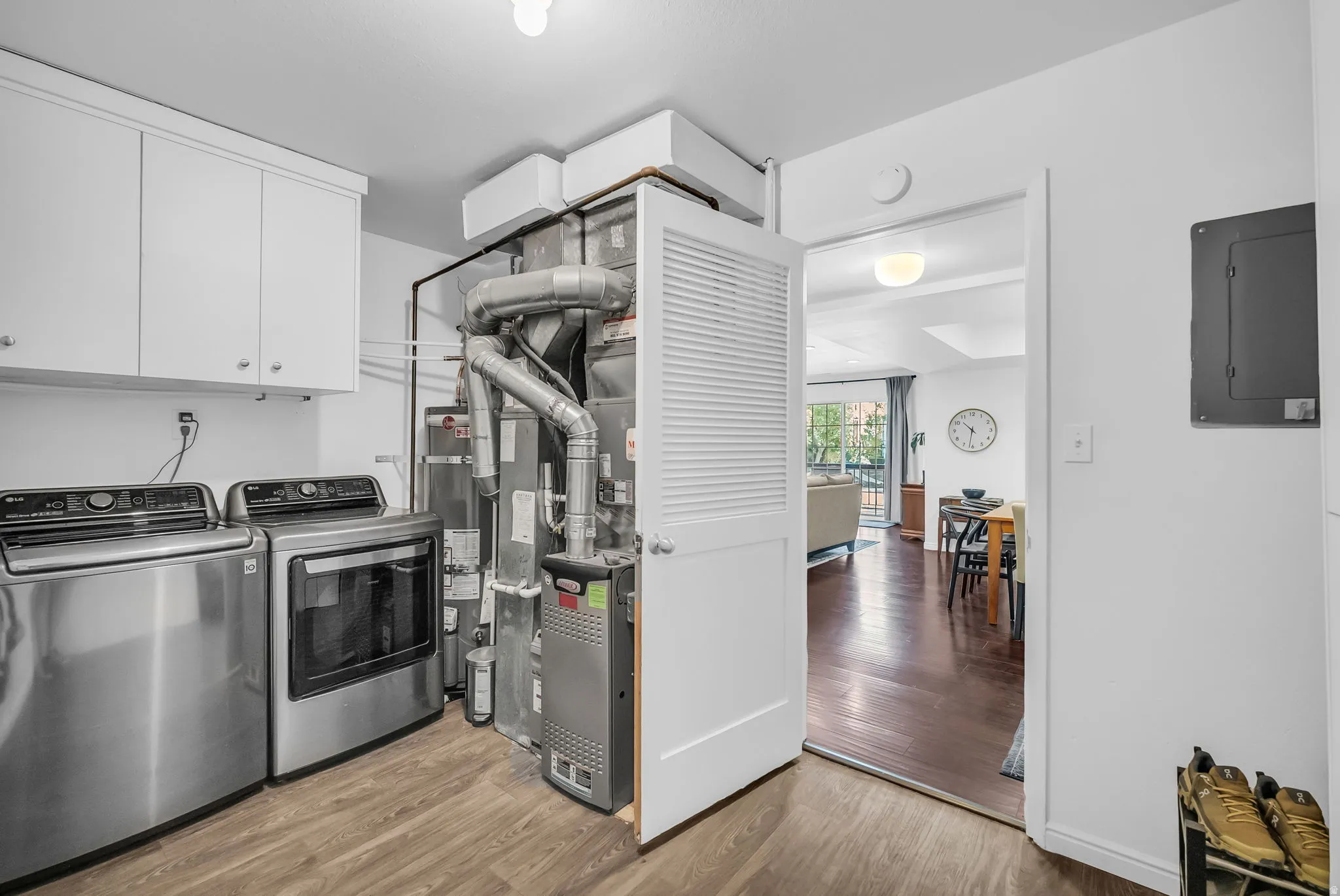 Updated kitchen featuring stainless steel appliances, white cabinetry, wood-finish flooring, and a utility closet with mechanical systems