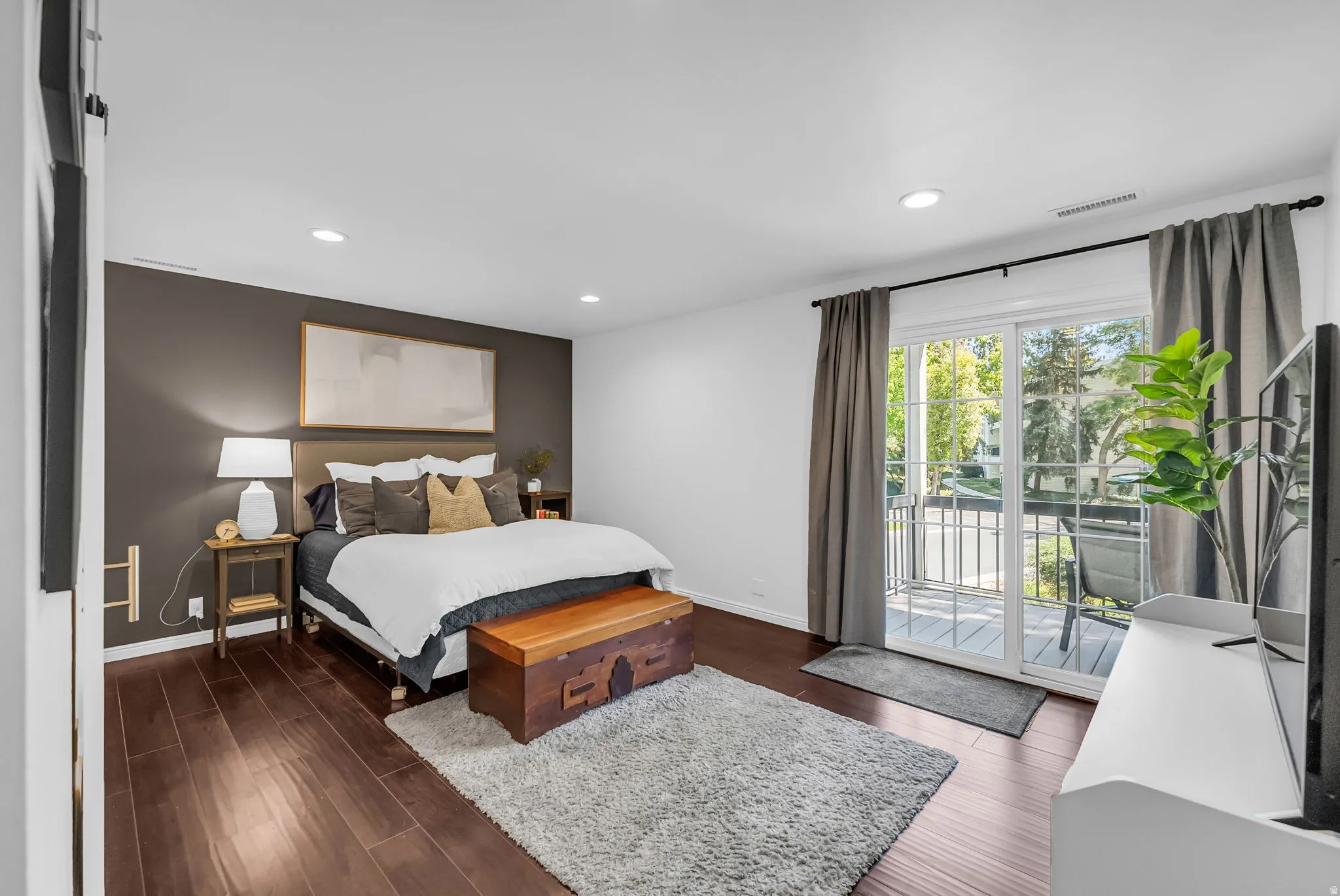 Spacious interior featuring rich wood-finish flooring, recessed lighting, and a private balcony with a sliding glass door