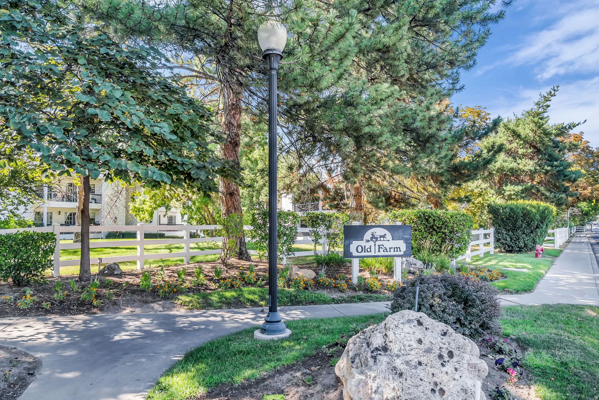 Welcoming entry featuring mature landscaping with established trees, manicured lawn, and professionally designed hardscaping