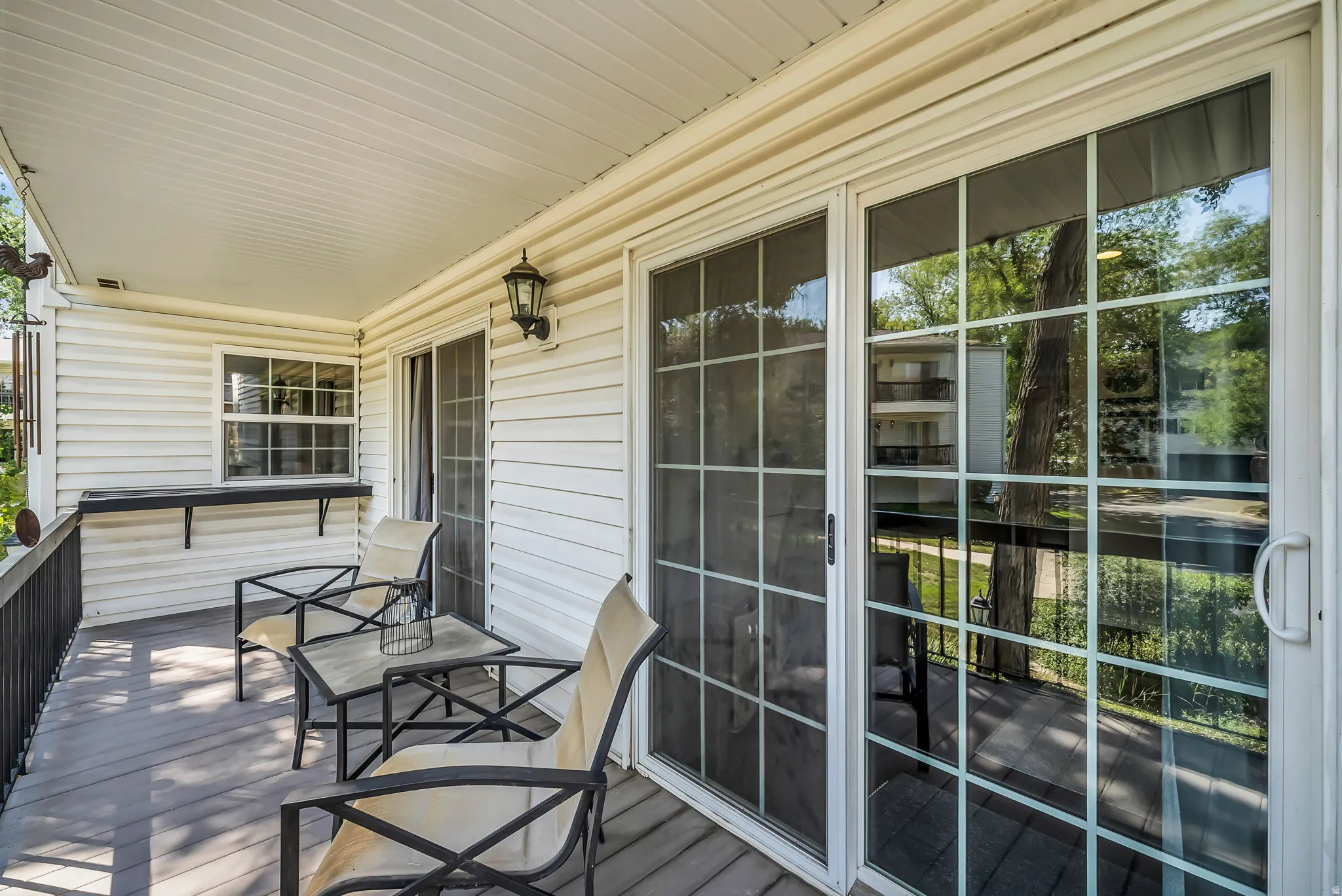 Covered deck with composite decking and ceiling, featuring sliding glass doors with multiple panes and black-framed sightlines