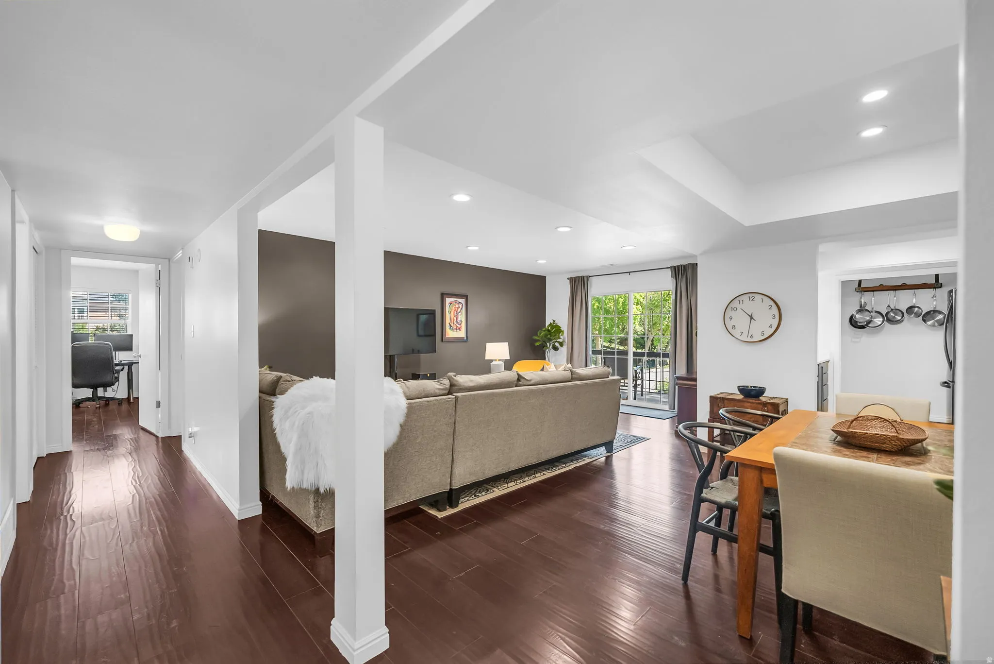 Open-concept living space anchored by white structural columns and featuring rich wood-finish flooring throughout