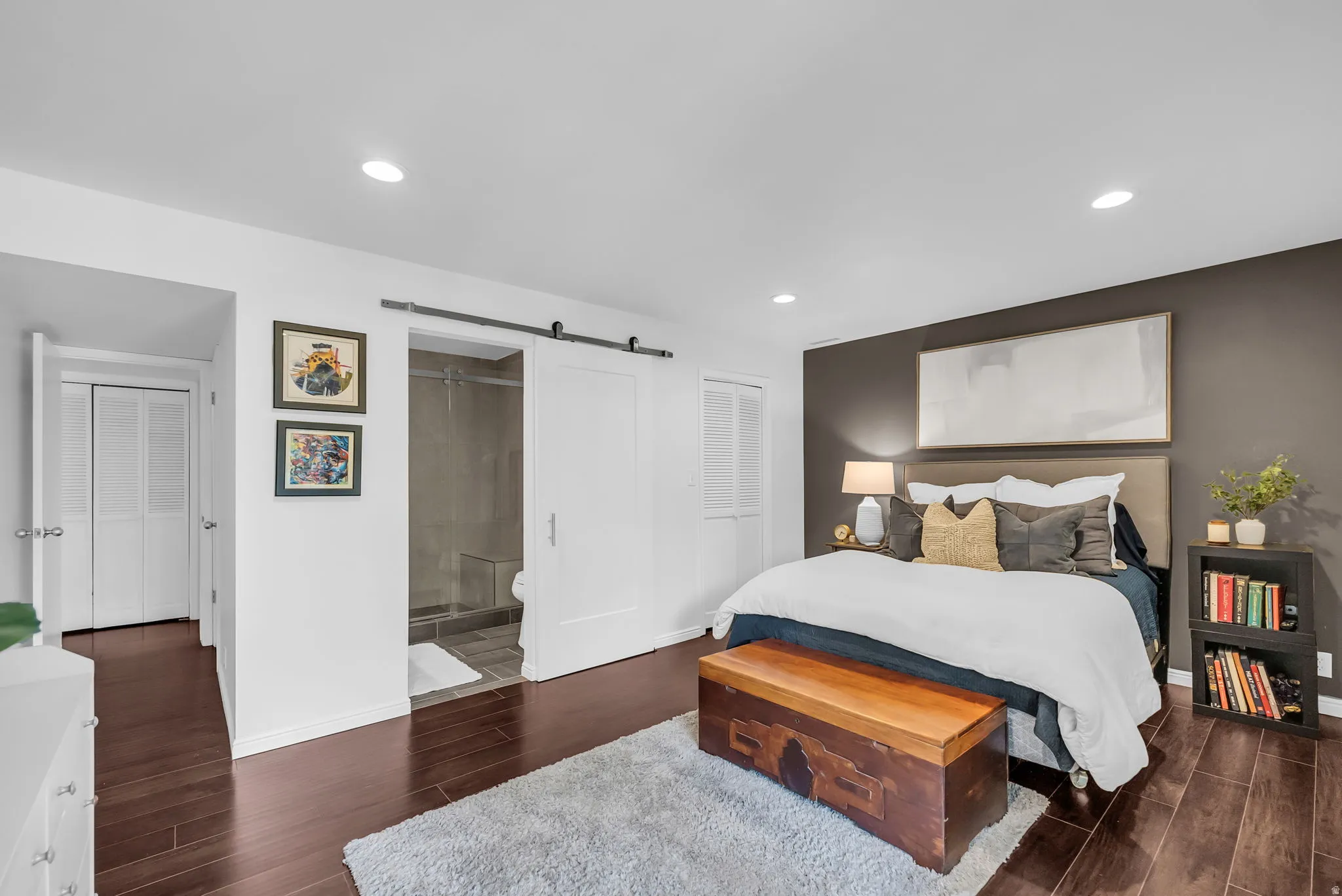 Bedroom featuring rich wood-finish flooring, recessed lighting, and a dark accent wall