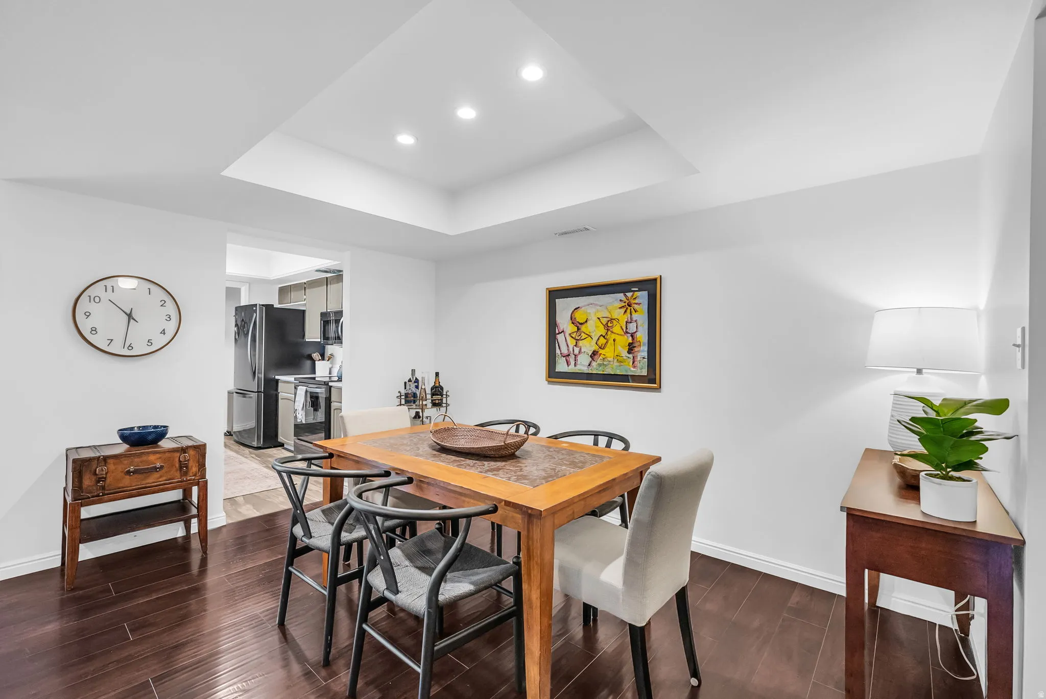 Elegant dining room featuring a wood-finish table with coordinating chairs, recessed ceiling lighting, and coffered ceiling detail