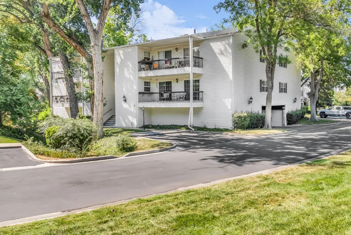 White-sided multi-unit residential building featuring clean architectural lines, black-trimmed windows, and covered balconies on each floor