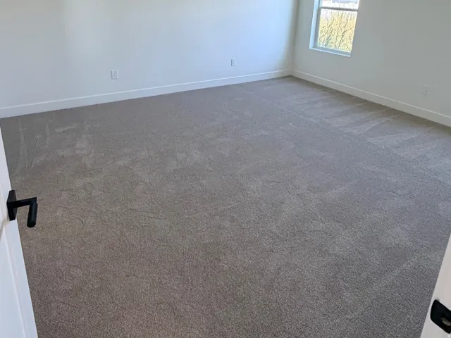Spacious room featuring neutral carpeting, white walls, a recessed ceiling light, a modern ceiling fan, and a single window