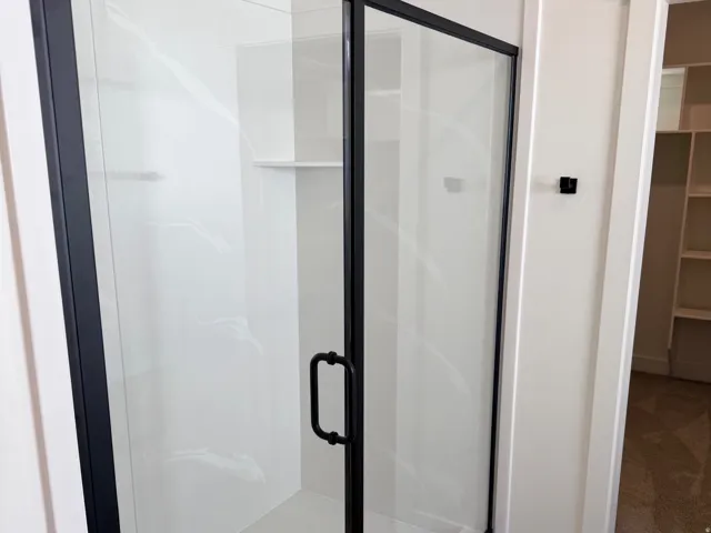 Enclosed shower featuring a clear glass door with matte black framing and hardware